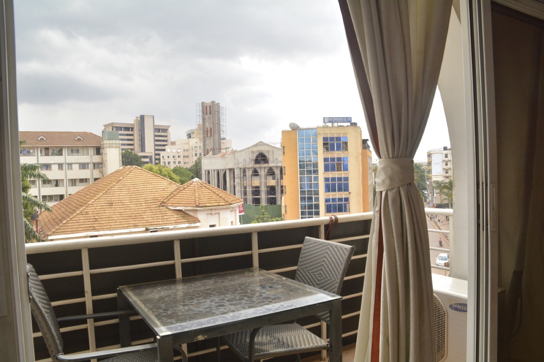 The balcony of an apartment at Shumuk House, table and chairs set out, looking over the rooftops of central Kampala