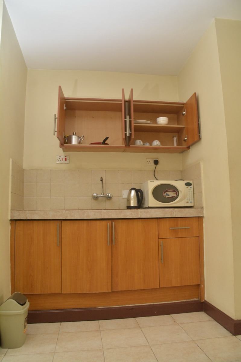 The kitchenette in a Shumuk House apartment, with units, a sink and a microwave